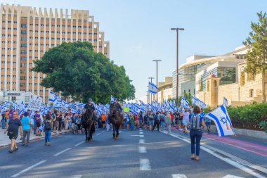 Hayfa, İsrail - 11 Temmuz 2023: Polis atlıları ve insanlar bayraklar ve çeşitli işaretlerle protesto ediyorlar. Hayfa, İsrail 'de tartışmalı yargı revizyonuna karşı bozulma günü