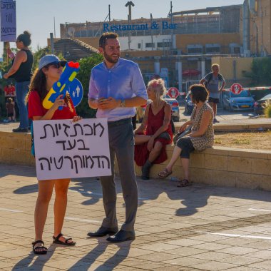 Hayfa, İsrail - 18 Temmuz 2023: İnsanlar tren istasyonunda bayraklar ve çeşitli tabelalarla protesto ediyorlar. Hayfa, İsrail 'de tartışmalı yargı revizyonuna karşı bozulma günü