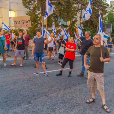 Hayfa, İsrail - 29 Temmuz 2023: İnsanlar slogan altında çeşitli işaretlerle yürüyorlar: Asla teslim olmayacağız. 30 haftalık tartışmalı adli elden geçirme protestosunun bir parçası. Hayfa, İsrail