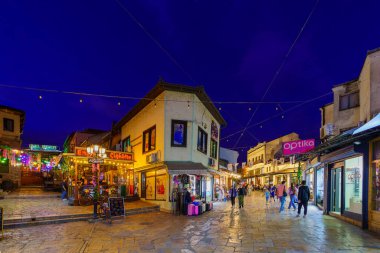 Üsküp, Kuzey Makedonya - 06 Ekim 2023: Eski Pazar semtinde dükkanlar, yerel halk ve ziyaretçilerle akşam sokak manzarası. Üsküp, Kuzey Makedonya