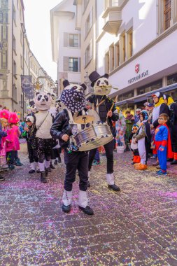 Lucerne, İsviçre - 21 Şubat 2023: Kostüm giymiş bir grup katılımcı ve kalabalık, İsviçre 'nin Lucerne kentinde düzenlenen Fasnacht Karnavalı' nın çocuk geçit töreninin bir parçası.