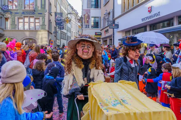 Lucerne, İsviçre - 21 Şubat 2023: Kostüm giymiş bir grup katılımcı ve kalabalık, İsviçre 'nin Lucerne kentinde düzenlenen Fasnacht Karnavalı' nın çocuk geçit töreninin bir parçası.