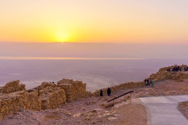Masada, İsrail - 19 Ocak 2024: Masada Kalesi 'nin kalıntılarının gündoğumu manzarası, ziyaretçiler ve arka planda Ölü Deniz, Judaean Çölü, güney İsrail