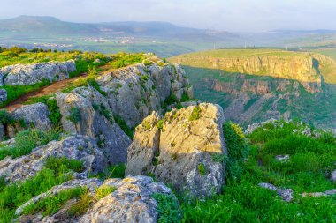 Kuzey İsrail 'deki Arbel Dağı Ulusal Parkı' nda kayaların, uçurumların, patikaların ve kır çiçeklerinin manzarası.