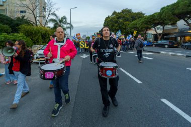 Hayfa, İsrail - 16 Mart 2024: İnsanlar hükümete karşı çeşitli tabelalar ve bayraklarla bir protesto yürüyüşüne katılarak yeni seçimler çağrısında bulundu. Hayfa, İsrail