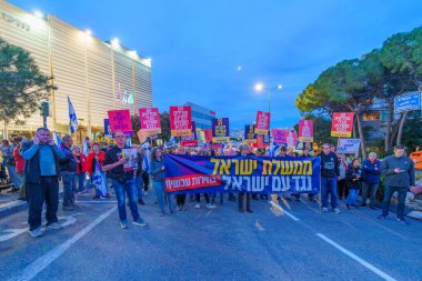 Hayfa, İsrail - 23 Mart 2024: İnsanlar, hükümete karşı çeşitli tabelalar ve bayraklarla yeni seçimler çağrısında bulunan bir protesto yürüyüşüne katıldılar. Hayfa, İsrail