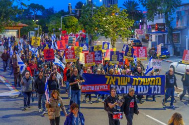 Haifa, Israel - March 23, 2024: People take part in a protest march, with various signs and flags, against the government, calling for new elections. Haifa, Israel clipart