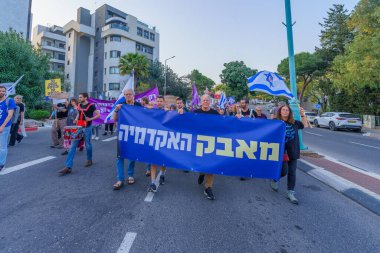 Hayfa, İsrail - 30 Mart 2024: İnsanlar, hükümete karşı çeşitli tabelalar ve bayraklarla yeni seçimler çağrısında bulunan bir protesto yürüyüşüne katılıyor. Hayfa, İsrail