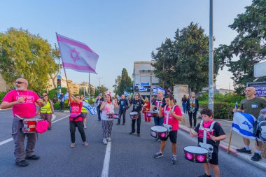 Hayfa, İsrail - 30 Mart 2024: İnsanlar, hükümete karşı çeşitli tabelalar ve bayraklarla yeni seçimler çağrısında bulunan bir protesto yürüyüşüne katılıyor. Hayfa, İsrail