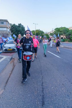 Hayfa, İsrail - 30 Mart 2024: İnsanlar, hükümete karşı çeşitli tabelalar ve bayraklarla yeni seçimler çağrısında bulunan bir protesto yürüyüşüne katılıyor. Hayfa, İsrail