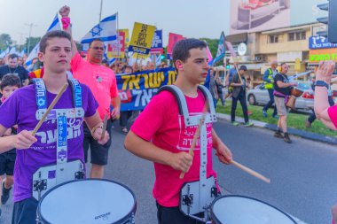 Hayfa, İsrail - 30 Mart 2024: İnsanlar, hükümete karşı çeşitli tabelalar ve bayraklarla yeni seçimler çağrısında bulunan bir protesto yürüyüşüne katılıyor. Hayfa, İsrail