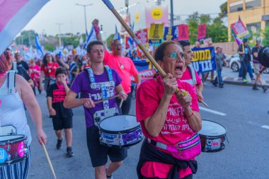 Hayfa, İsrail - 30 Mart 2024: İnsanlar, hükümete karşı çeşitli tabelalar ve bayraklarla yeni seçimler çağrısında bulunan bir protesto yürüyüşüne katılıyor. Hayfa, İsrail