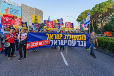 Hayfa, İsrail - 30 Mart 2024: İnsanlar, hükümete karşı çeşitli tabelalar ve bayraklarla yeni seçimler çağrısında bulunan bir protesto yürüyüşüne katılıyor. Hayfa, İsrail