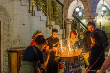 Jerusalem, Israel - March 29, 2024: Western good Friday scene in the church of the holy Sepulchre, with pilgrim lighting candles. Old city of Jerusalem, Israel clipart