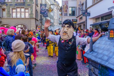 Lucerne, İsviçre - 21 Şubat 2023: Kostüm giymiş bir grup katılımcı ve kalabalık, İsviçre 'nin Lucerne kentinde düzenlenen Fasnacht Karnavalı' nın çocuk geçit töreninin bir parçası.