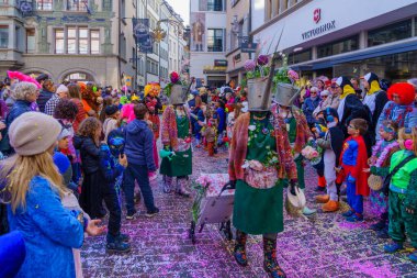 Lucerne, İsviçre - 21 Şubat 2023: Kostüm giymiş bir grup katılımcı ve kalabalık, İsviçre 'nin Lucerne kentinde düzenlenen Fasnacht Karnavalı' nın çocuk geçit töreninin bir parçası.