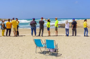 HaBonim, İsrail - 19 Nisan 2024: Rehinelerin ailelerini desteklemek için sırada bekleyen insanlarla birlikte İsrail sahillerinde omuzdan Sholder etkinliği. HaBonim Sahili, İsrail