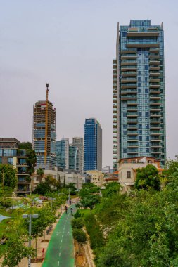 Tel-Aviv, Israel - May 10, 2024: View of HaMesila park, and skyscraper buildings, with visitors, in Tel-Aviv, Israel clipart