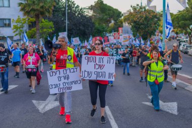 Hayfa, İsrail - 18 Mayıs 2024: İnsanlar, hükümete karşı çeşitli tabelalar ve bayraklarla yeni seçimler çağrısında bulunan bir protesto yürüyüşüne katılıyor. Hayfa, İsrail