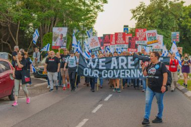 Hayfa, İsrail - 18 Mayıs 2024: İnsanlar, hükümete karşı çeşitli tabelalar ve bayraklarla yeni seçimler çağrısında bulunan bir protesto yürüyüşüne katılıyor. Hayfa, İsrail