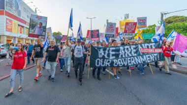 Hayfa, İsrail - 18 Mayıs 2024: İnsanlar, hükümete karşı çeşitli tabelalar ve bayraklarla yeni seçimler çağrısında bulunan bir protesto yürüyüşüne katılıyor. Hayfa, İsrail