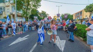 Hayfa, İsrail - 18 Mayıs 2024: İnsanlar, hükümete karşı çeşitli tabelalar ve bayraklarla yeni seçimler çağrısında bulunan bir protesto yürüyüşüne katılıyor. Hayfa, İsrail