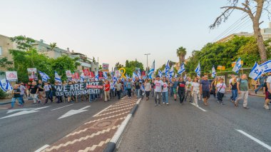 Hayfa, İsrail - 18 Mayıs 2024: İnsanlar, hükümete karşı çeşitli tabelalar ve bayraklarla yeni seçimler çağrısında bulunan bir protesto yürüyüşüne katılıyor. Hayfa, İsrail