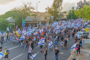 Hayfa, İsrail - 25 Mayıs 2024: İnsanlar, hükümete karşı çeşitli tabelalar ve bayraklarla yeni seçimler çağrısında bulunan bir protesto yürüyüşüne katıldılar. Hayfa, İsrail