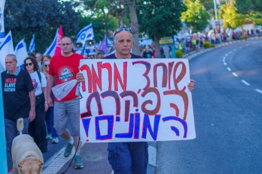 Hayfa, İsrail - 01 Haziran 2024: İnsanlar hükümete karşı çeşitli tabelalar ve bayraklarla yeni seçimler çağrısında bulunarak bir protesto yürüyüşüne katılıyor. Hayfa, İsrail