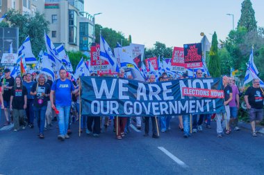 Hayfa, İsrail - 01 Haziran 2024: İnsanlar hükümete karşı çeşitli tabelalar ve bayraklarla yeni seçimler çağrısında bulunarak bir protesto yürüyüşüne katılıyor. Hayfa, İsrail