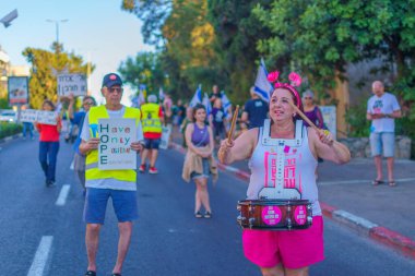 Hayfa, İsrail - 01 Haziran 2024: İnsanlar hükümete karşı çeşitli tabelalar ve bayraklarla yeni seçimler çağrısında bulunarak bir protesto yürüyüşüne katılıyor. Hayfa, İsrail