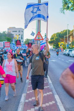 Hayfa, İsrail - 01 Haziran 2024: İnsanlar hükümete karşı çeşitli tabelalar ve bayraklarla yeni seçimler çağrısında bulunarak bir protesto yürüyüşüne katılıyor. Hayfa, İsrail