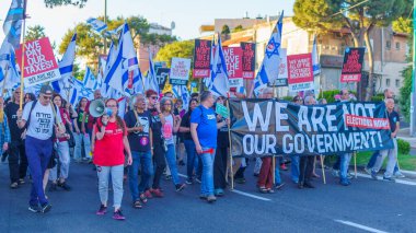 Hayfa, İsrail - 01 Haziran 2024: İnsanlar hükümete karşı çeşitli tabelalar ve bayraklarla yeni seçimler çağrısında bulunarak bir protesto yürüyüşüne katılıyor. Hayfa, İsrail