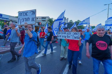 Hayfa, İsrail - 01 Haziran 2024: İnsanlar hükümete karşı çeşitli tabelalar ve bayraklarla yeni seçimler çağrısında bulunarak bir protesto yürüyüşüne katılıyor. Hayfa, İsrail