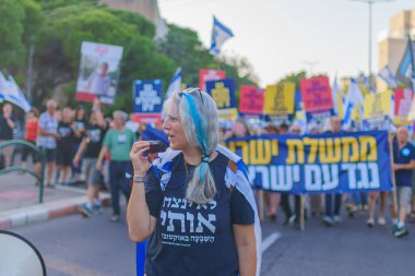 Hayfa, İsrail - Haziran 08, 2024: İnsanlar hükümete karşı çeşitli tabelalar ve bayraklarla yeni seçimler çağrısında bulunarak bir protesto yürüyüşüne katılıyor. Hayfa, İsrail