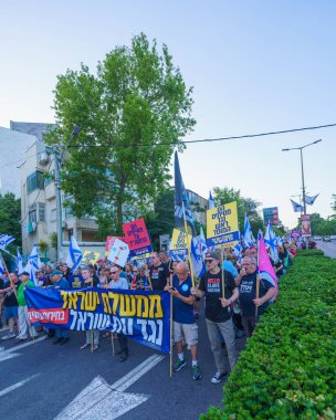 Hayfa, İsrail - Haziran 08, 2024: İnsanlar hükümete karşı çeşitli tabelalar ve bayraklarla yeni seçimler çağrısında bulunarak bir protesto yürüyüşüne katılıyor. Hayfa, İsrail