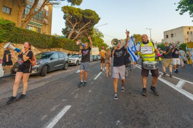 Hayfa, İsrail - 15 Haziran 2024: İnsanlar hükümete karşı çeşitli tabela ve bayraklarla bir protesto yürüyüşüne katılarak yeni seçimler çağrısında bulundu. Hayfa, İsrail