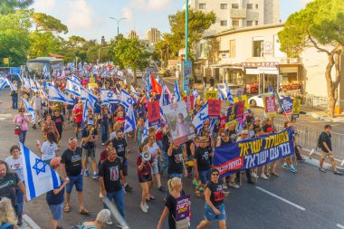 Hayfa, İsrail - 22 Haziran 2024: İnsanlar hükümete karşı çeşitli tabela ve bayraklarla bir protesto yürüyüşüne katılarak yeni seçimler çağrısında bulundu. Hayfa, İsrail