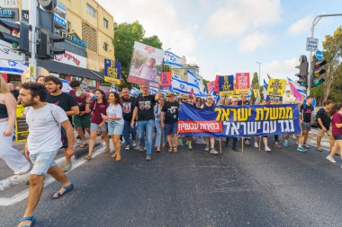 Hayfa, İsrail - 22 Haziran 2024: İnsanlar hükümete karşı çeşitli tabela ve bayraklarla bir protesto yürüyüşüne katılarak yeni seçimler çağrısında bulundu. Hayfa, İsrail