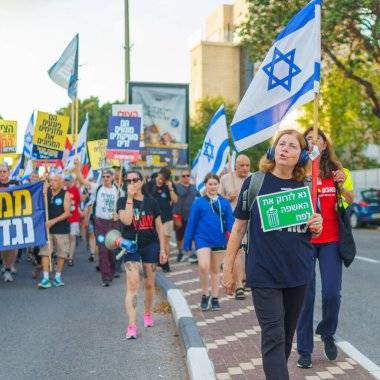 Hayfa, İsrail - 22 Haziran 2024: İnsanlar hükümete karşı çeşitli tabela ve bayraklarla bir protesto yürüyüşüne katılarak yeni seçimler çağrısında bulundu. Hayfa, İsrail