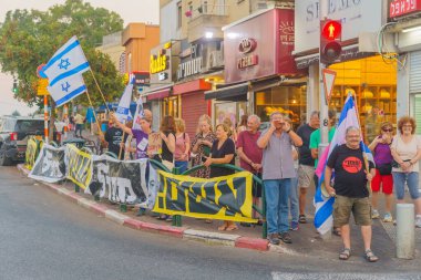 Hayfa, İsrail - 27 Haziran 2024: Çeşitli tabela ve bayraklara sahip insanlar hükümeti protesto ederek yeni seçim çağrısında bulundular. Hayfa, İsrail