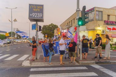 Hayfa, İsrail - 27 Haziran 2024: Çeşitli tabela ve bayraklara sahip insanlar hükümeti protesto ederek yeni seçim çağrısında bulundular. Hayfa, İsrail