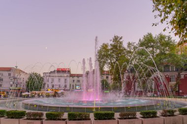 Varna, Bulgaristan - 22 Eylül 2023: Yerel halk ve ziyaretçilerle birlikte Independence Meydanı ve çeşmesinin gün batımı manzarası, Varna, Bulgaristan