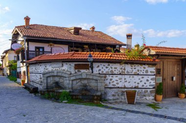 Bansko, Bulgaristan - 30 Eylül 2023: Bulgaristan 'ın güneybatısındaki Bansko kentinde tipik binalar, yerel halk ve ziyaretçilerin yer aldığı sokak sahnesi