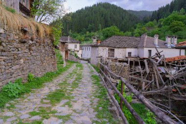 Bulgaristan 'ın güneyindeki Shiroka Laka, Rodop Dağları' nda tipik binalara sahip bir caddenin gün batımı manzarası