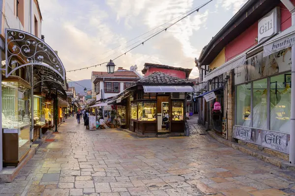 Üsküp, Kuzey Makedonya - 06 Ekim 2023: Eski Pazar semtinde dükkanlar, yerel halk ve ziyaretçilerle gün batımı sokak sahnesi. Üsküp, Kuzey Makedonya