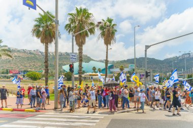 Hayfa, İsrail - 07 Temmuz 2024: İnsanlar büyük bir kavşağı tıkayan bayraklar, çeşitli işaretlerle protesto ediyorlar. Hükümete ve rehine ailelerine, Hayfa 'ya ve İsrail' e karşı yapılan müdahalenin bir parçası.