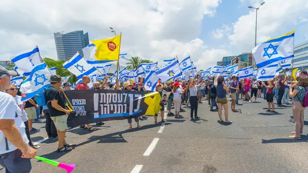 Stock image Haifa, Israel - July 07, 2024: People protest with flags, various signs, blocking a major junction. Part of day of disruption against the government and support of hostages families, Haifa, Israel