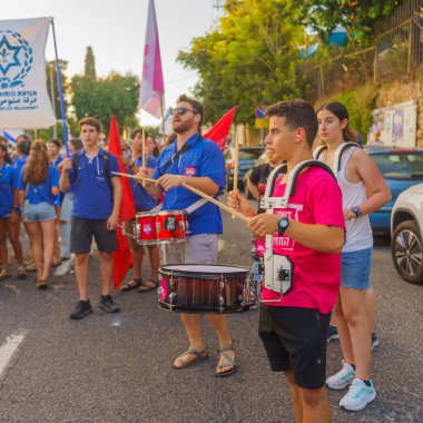 Hayfa, İsrail - Temmuz 06, 2024: İnsanlar hükümete karşı çeşitli işaret ve bayraklarla yeni seçimler çağrısında bulunan bir protesto yürüyüşüne (Hashomer Hatzair gençlik hareketi) katılıyor. Hayfa, İsrail