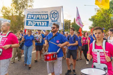 Hayfa, İsrail - Temmuz 06, 2024: İnsanlar hükümete karşı çeşitli işaret ve bayraklarla yeni seçimler çağrısında bulunan bir protesto yürüyüşüne (Hashomer Hatzair gençlik hareketi) katılıyor. Hayfa, İsrail